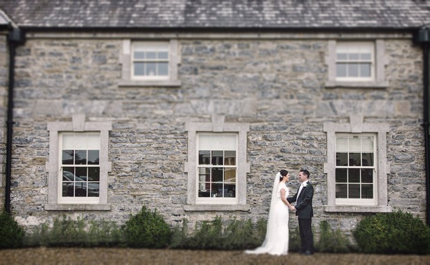 bride and groom in front of stone wall